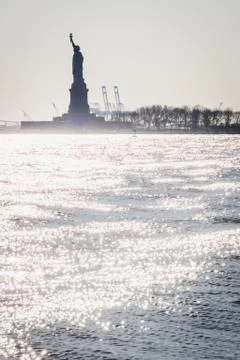 Statue of Liberty shape against the light from Lower Manhattan Stock Photos