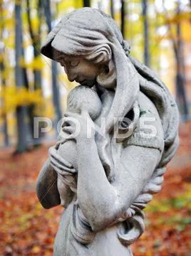 Statue of madonna and child in autumn forest Stock Photos