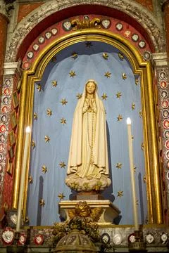 Statue of the Madonna in prayer with two lighted candles on the sides Stock Photos