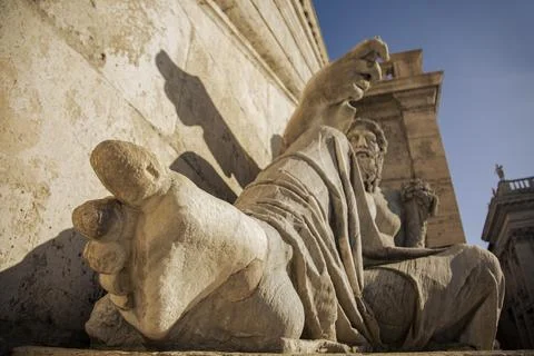 A statue of a man with big toe in foreground laying on a stone base. Rome Stock Photos