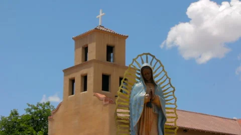 Statue of the Our Lady of Guadalupe in front of an Adobe Church Stock Footage 64834329