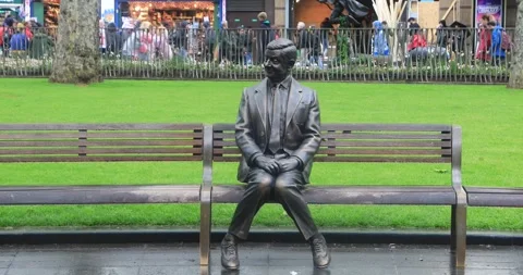 Statue of Rowan Atkinson comic character sits on bench Leicester Square London Stock Footage 321017489