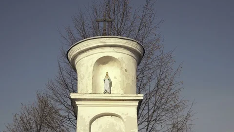 Statue of Virgin Mary with Jesus. Small Christian cross, blue sky in background Stockbeeldmateriaal 104138853