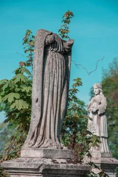 Statue without a head on a grave on an old cemetery. Vintage style Stock Photos