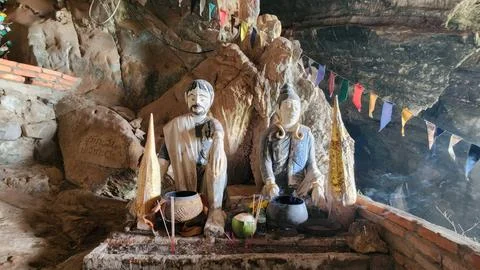 Statues of Deities in Cave Temple Surrounded by Colorful Flags Stock Photos