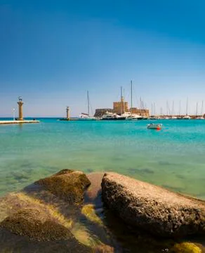 Statues stand either side of Mandraki harbour entrance Stock Photos