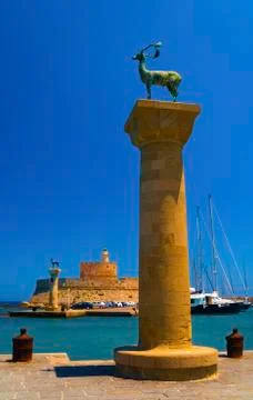 Statues stand either side of Mandraki harbour entrance Stock Photos