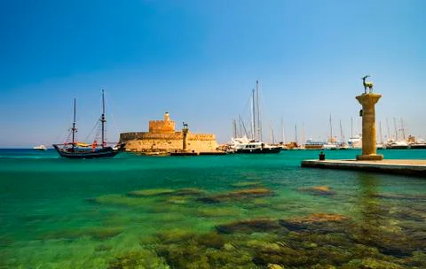Statues stand either side of Mandraki harbour entrance Stock Photos