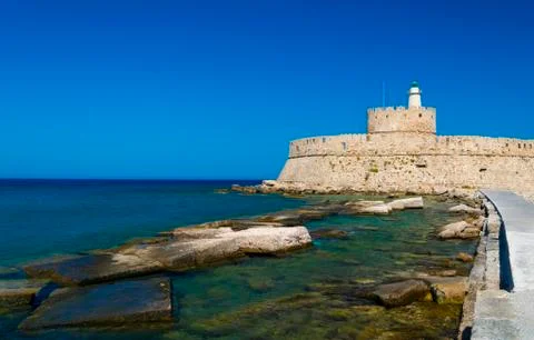 Statues stand either side of Mandraki harbour entrance Stock Photos