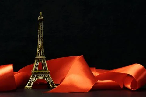 A statuette of the Eiffel Tower surrounded by a red ribbon on a black . The c Foto stock