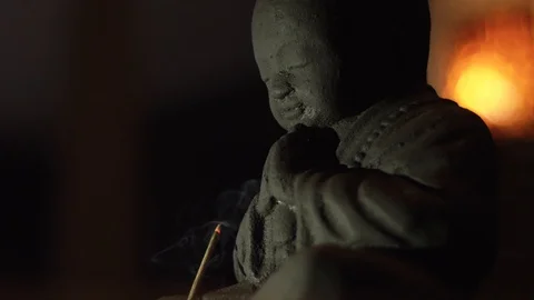 Statuette of a small buddha, in front of which an aroma candle is smoldering Video stock 105256797