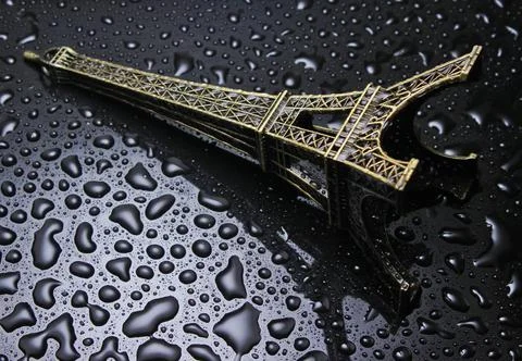Statuette of the tower of Eifel with water drops on a black background.. Stock Photos