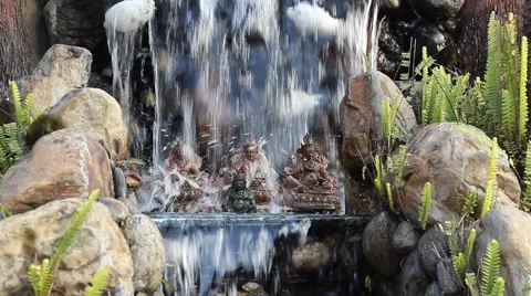 Statuettes with the image of Buddhas under a waterfall Stock Footage 58990328