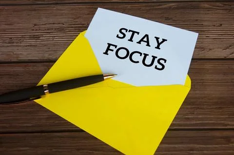 Stay focus text on white notepad with envelope on wooden desk background. F.. Stock Photos