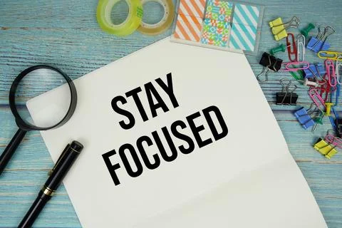 Stay Focused text written on notepad with magnifying glass flat lay on wood.. Stock Photos