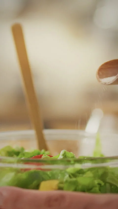 Stay at home parent preparing a fresh salad with a sprinkle of salt in a coz Stock Footage 331728962