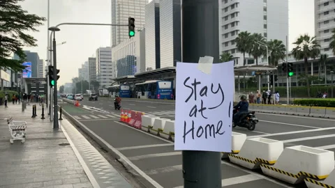A "Stay at Home" Reminder Placed on A Pole Near Traffic Light in Jakarta Stock Footage