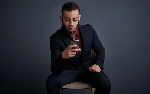 Staying up to date via text. Studio shot of a stylish young businessman sending Stock Photos