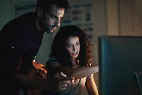 Staying productive while the world sleeps. two colleagues using a computer 스톡 사진