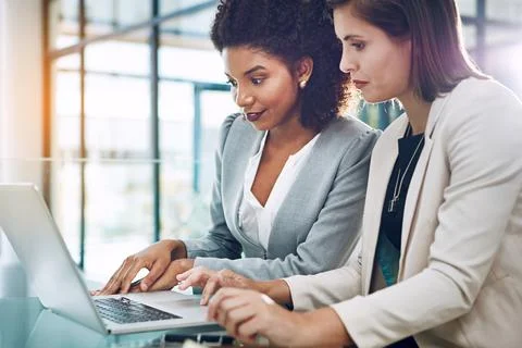 Staying on track with tech and teamwork. two young businesswomen using a laptop Stock Photos