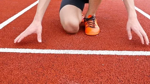 Steadicam around track runner boy teenager at starting line, slow motion Stock Footage