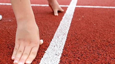Steadicam close detail of track runner woman with hands at starting line Stock Footage
