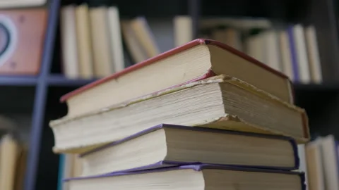 Steadicam shot, 4K. Camera moves around the stacked books near a book shelf Stock Footage 163908619