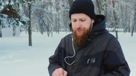 Steadicam shot: Attractive bearded man walking in a winter park, enjoys a tablet Stock Footage 65891963