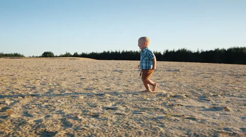 Steadicam shot: Cool kid running across the sand, rejoices. Slow-motion video Stock Footage 65761637