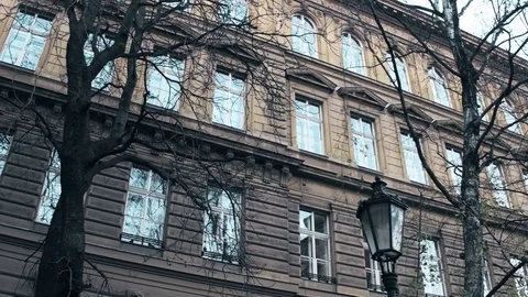 Steadicam shot of leafless trees against the classical european building in Stock Footage 70471422