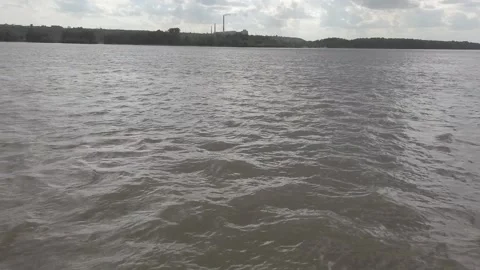 Steadicam shot from left side of boat on the river with distant plant smoking Stock Footage 164893146