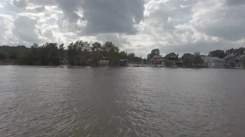 Steadicam shot from left side boat on the river with distant houses on shore Stock Footage 164893148