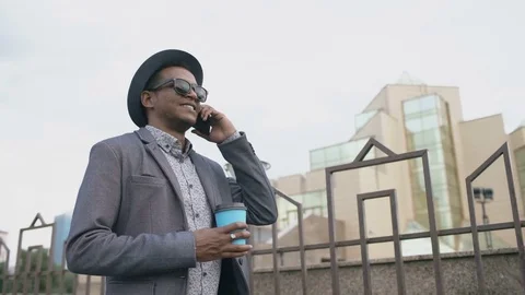 Steadicam shot of Mafia man in suit and sunglasses talking phone and walking Stock Footage