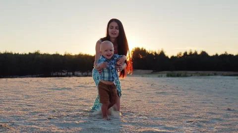 Steadicam shot: Mom plays with her little son at sunset. Kid runs towards the Stock Footage 65763477