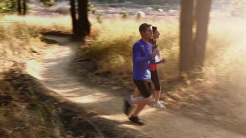 Steadicam shot of running couple drinking water while running on mountain trail. Stock Footage 199630587