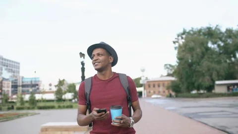Steadicam shot of smiling tourist man walking and surfing smartphone near famous Stock Footage