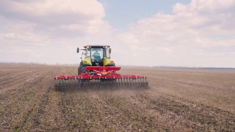 Steadicam shot: Two tractors go ahead on the field, cultivate the ground Stock Footage