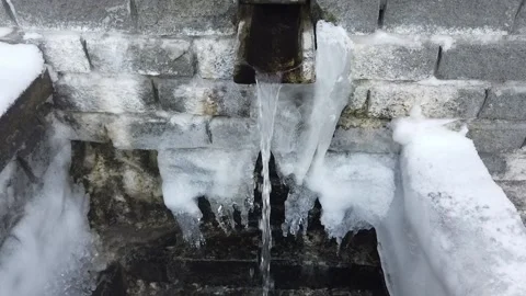 Steadicam shot of winter gushing spring out of a brick wall with ice and icicles 動画素材 165025808