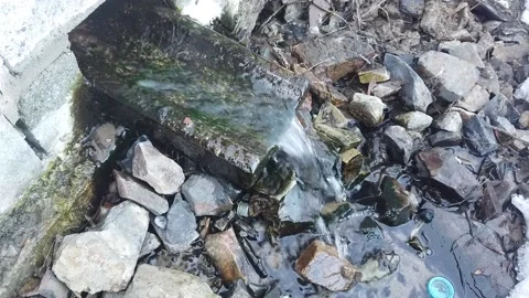 Steadicam shot of winter gushing spring out of a brick wall with some ice Stock Footage 165025823