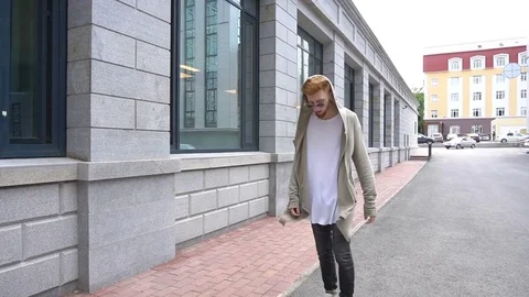 Steadicam shot of a young red haired man in stylish clothes is walking around Stock Footage 78928992