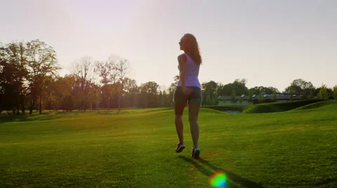 Steadicam slow motion shot: Beautiful young woman running on the green grass Stock Footage 65522906