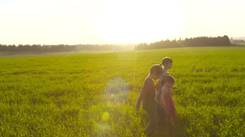 Steady cam shot of three kids walking in a green field Stock Footage 59180530