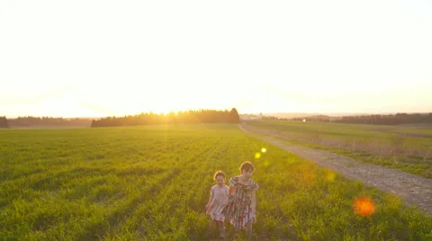 Steady Cam shot of two girls running in a field during sunset Stock Footage 59181711