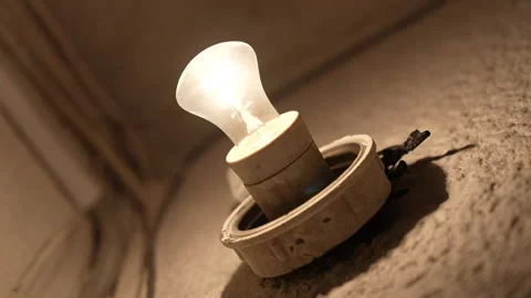 Steady glowing light bulb on textured wall in vintage apartment corridor Vidéo 325802129