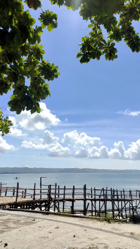 Steady Handheld Tranquil Beach with Distant Boats Clear Blue Sky bamboo pier Stockbeeldmateriaal 274304385