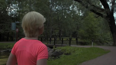Steady shot, camera flying around woman running in the park. Medium shot. 스톡 동영상 114506912