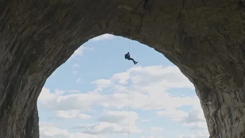 Steady Shot of Climber Rappelling from Cave Arch in Romania Stock Footage 345632536