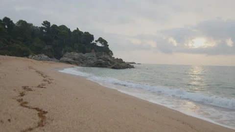 Steady shot at the edge of the wild beach at cloudy sunrise, in Spain Stock Footage 230097901