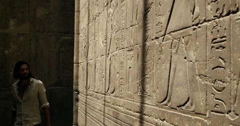 A steady shot of an Egyptologist walking between pharaonic symbols Video stock 209949684