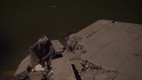 Steady shot of a man making indian naan by the river Ganga Stock Footage 114659698